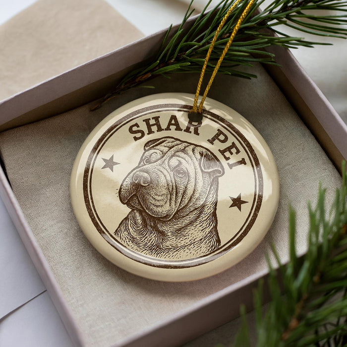 A circular ornament featuring a dog's face with the text "SHARPE PEP" on it, placed in a box with pine branches.