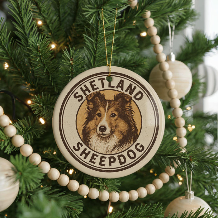 A Christmas tree decorated with a circular ornament featuring a Shetland Sheepdog image, surrounded by beaded ornaments and twinkling lights.