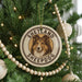 A Christmas tree decorated with a circular ornament featuring a Shetland Sheepdog image, surrounded by beaded ornaments and twinkling lights.