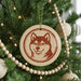 A Christmas tree decorated with ornaments, including a circular ornament featuring a red and white dog face.