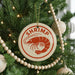 A Christmas tree decorated with ornaments, including a circular ornament with a shrimp design and a string of beads.