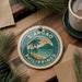 A round ornament with the text "SIARGAO PHILIPPINES" and a tropical beach scene, hanging on a wooden surface.