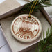 A ceramic ornament in a box, featuring a close-up image of a tiger's face.