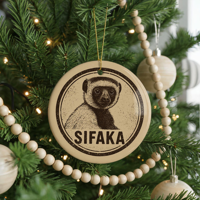 A Christmas tree decorated with ornaments, including a circular ornament with a picture of a lemur and the word "SIFAKA" written on it.