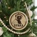 A Christmas tree decorated with ornaments, including a circular ornament with a picture of a lemur and the word "SIFAKA" written on it.
