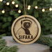 A circular ornament featuring a close-up image of a lemur, with the word "SIFAKA" written below it.