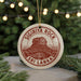 A circular ornament with the text "SIGIRIYA ROCK" and "SRI LANKA" printed on it, hanging from a string.