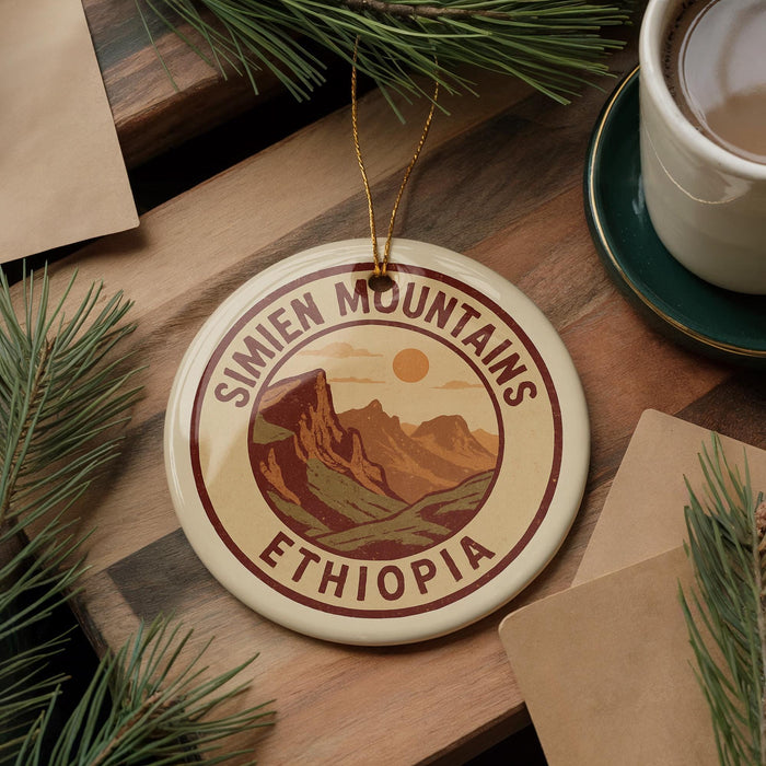 a circular ornament with the text "SIMIEN MOUNTAINS ETHIOPIA" on it, surrounded by pine branches and a cup of coffee on a wooden surface.