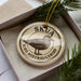 A circular ornament with the text "SKUA BIRD AUSTRALILDB" printed on it, surrounded by pine branches.
