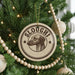 A Christmas tree decorated with ornaments, including a circular ornament with a dog's head and the word "SLOUGHI" written on it.