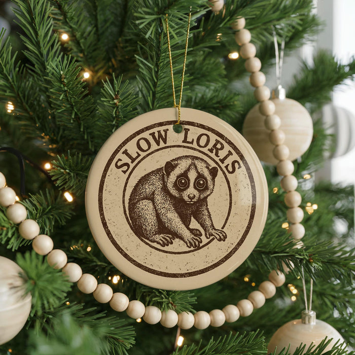 A Christmas tree decorated with ornaments, including a circular ornament with a picture of a slow Loris, a type of primate.