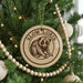 A Christmas tree decorated with ornaments, including a circular ornament with a picture of a slow Loris, a type of primate.