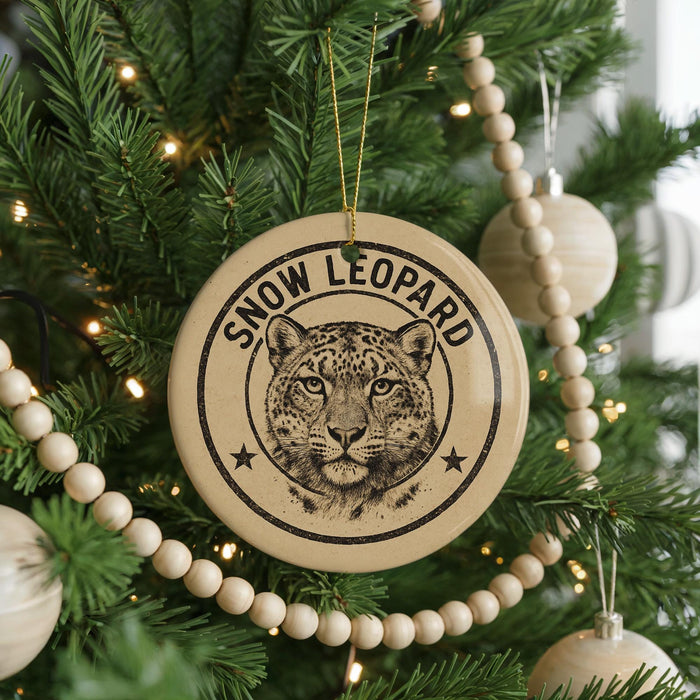 A Christmas tree decorated with ornaments, including a large circular ornament with a leopard's face and the text "SNOW LEOPARD" printed on it.