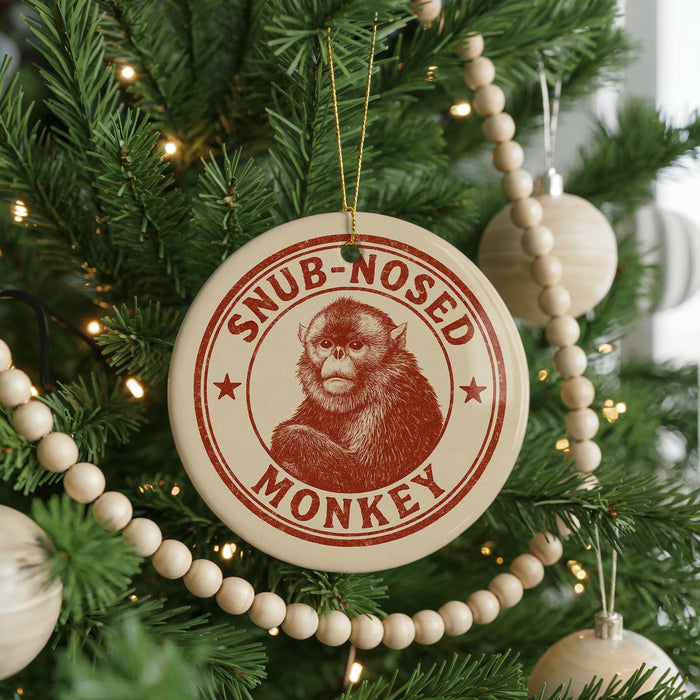 A Christmas tree decorated with ornaments, including a circular ornament with a monkey image and the text "SNUB-NOSED MONKEY" printed on it.