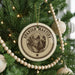 A round ornament with a dog's face on it, hanging from a Christmas tree.