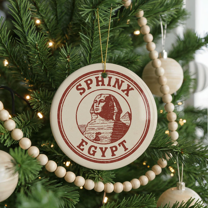 A Christmas tree decorated with ornaments, including a circular ornament with the text "SPHINX EGYPT" and a wooden bead decoration.