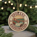 A round ornament with the text "SPOKANE WASHINGTON" and an illustration of a waterfall and bridge, hanging from a string.