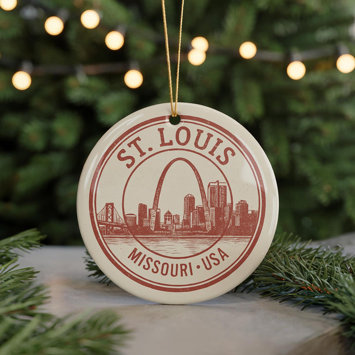 A circular ornament with a red and white design featuring the St. Louis, Missouri skyline and the text "St. Louis Missouri - USA" is displayed on a Christmas tree.