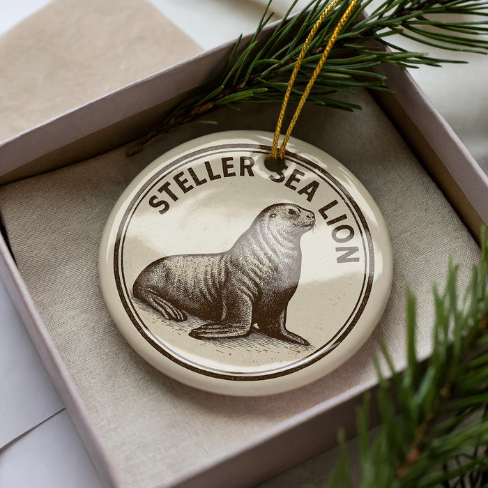 A round ornament with a seal on it, placed inside a box with pine branches.