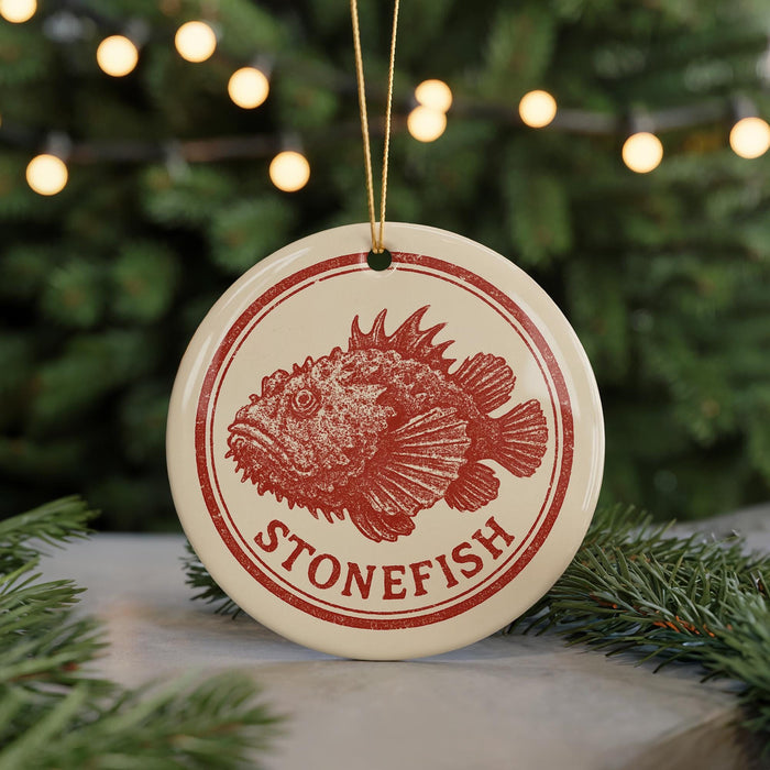 A round ornament with a red and white design featuring a fish, hanging from a string.