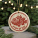 A round ornament with a red and white design featuring a fish, hanging from a string.