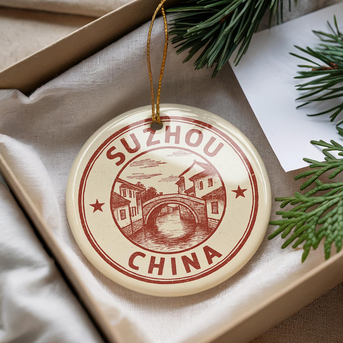 A decorative ornament with the text "SUZHOU CHINA" and an illustration of a bridge is displayed in a box, surrounded by pine branches.