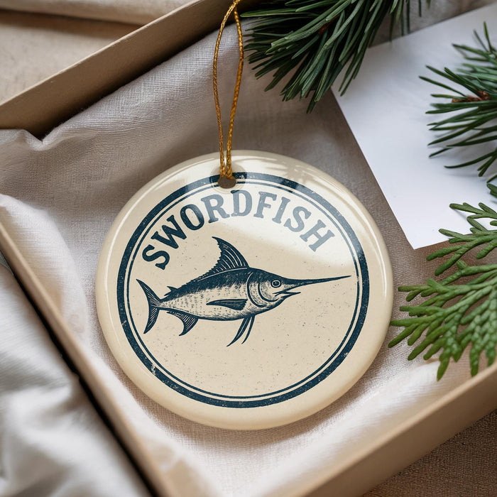 A round ornament with the text "SWORDFISH" and a graphic of a swordfish is displayed in a box, surrounded by pine branches.
