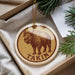 A circular ornament with a brown buffalo illustration and the word "Takin" printed on it, hanging from a string.