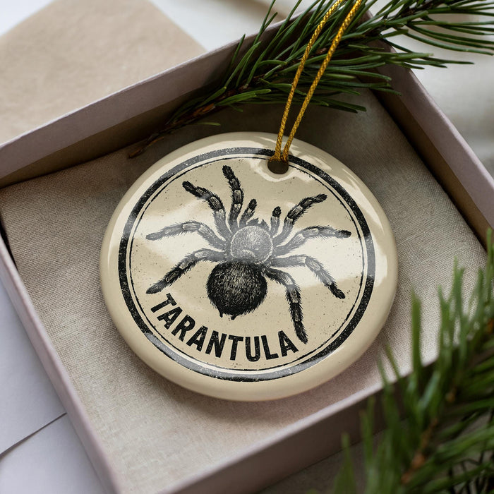 A circular ornament with a black and white illustration of a tarantula, surrounded by a yellow string.
