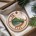 A round ornament with a tropical island design and the text "TAVEUNI Fiji" is displayed in a box with pine branches.
