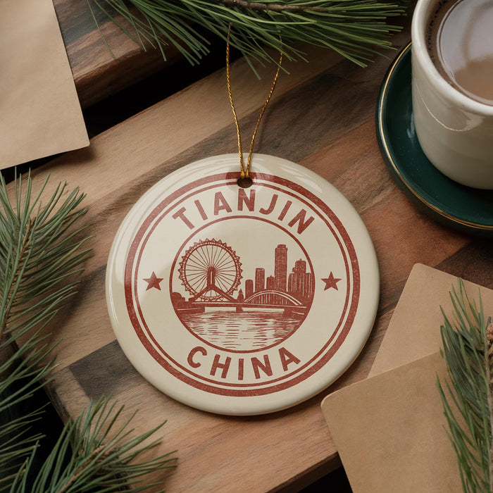 A circular ornament with the text "TIANJIN CHINA" and an illustration of a ferris wheel and city skyline, hanging on a wooden surface.