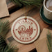 A circular ornament with the text "TIANJIN CHINA" and an illustration of a ferris wheel and city skyline, hanging on a wooden surface.