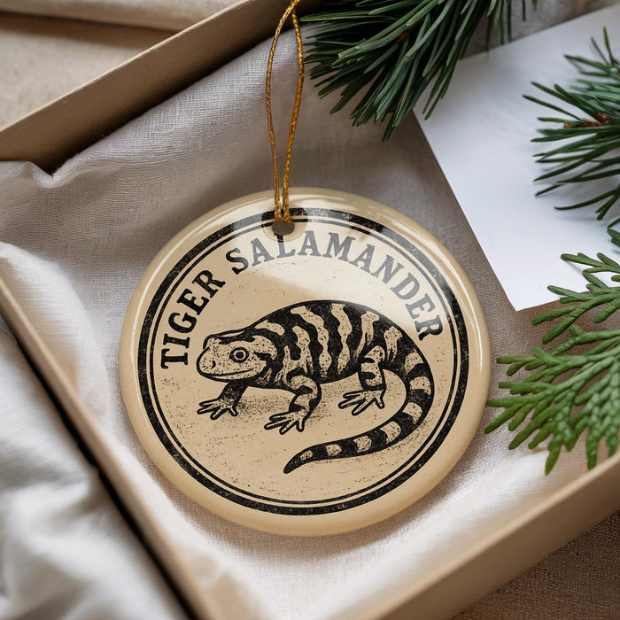 A decorative ornament featuring a tiger salamander, which is a type of salamander, is displayed in a box with pine branches.
