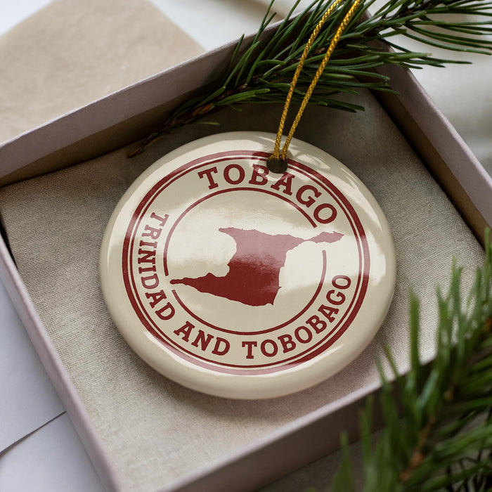 A circular ornament with the text "TOBAGO TRINIDAD AND TOBAGO" printed on it, surrounded by pine branches.