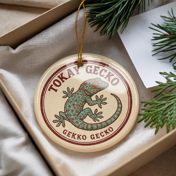 A circular ornament with a green and brown lizard design, hanging from a string.