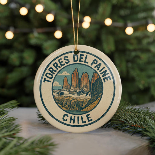 A round ornament with the text "TORRES DEL PAINE CHILE" and an illustration of a mountain range, hanging from a string.