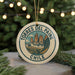 A round ornament with the text "TORRES DEL PAINE CHILE" and an illustration of a mountain range, hanging from a string.