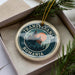 A circular ornament with the text "TRANSYLVANIA ROMANIA" and a castle illustration, placed in a box with pine branches.