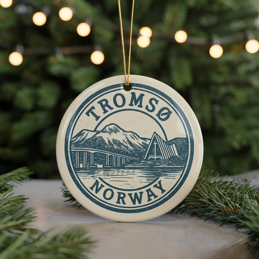 A circular ornament with the text "TROMSO NORWAY" and an illustration of a mountain and bridge, hanging from a string.