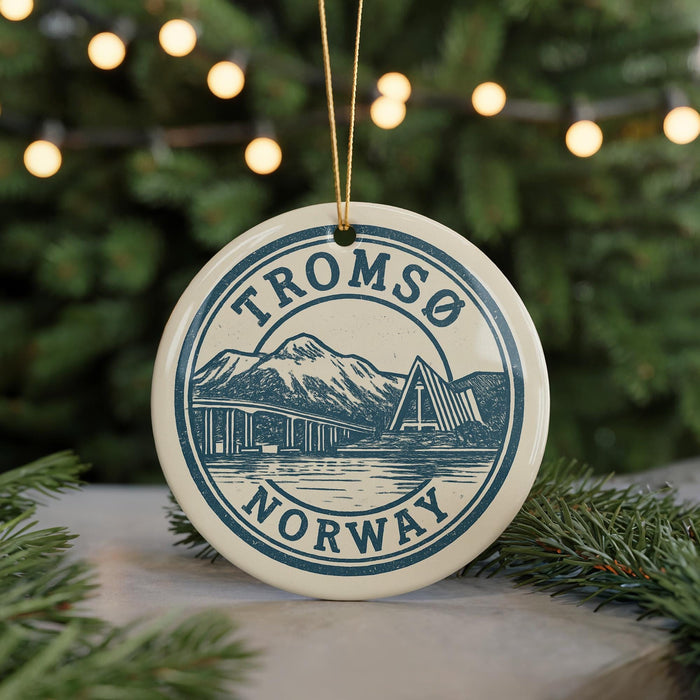 A circular ornament with the text "TROMSO NORWAY" and an illustration of a mountain and bridge, hanging from a string.