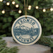 A circular ornament with the text "TROMSO NORWAY" and an illustration of a mountain and bridge, hanging from a string.