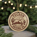 A circular ornament with the text "TUCSON ARIZONA US" printed on it, featuring a desert landscape with cacti and mountains in the background.