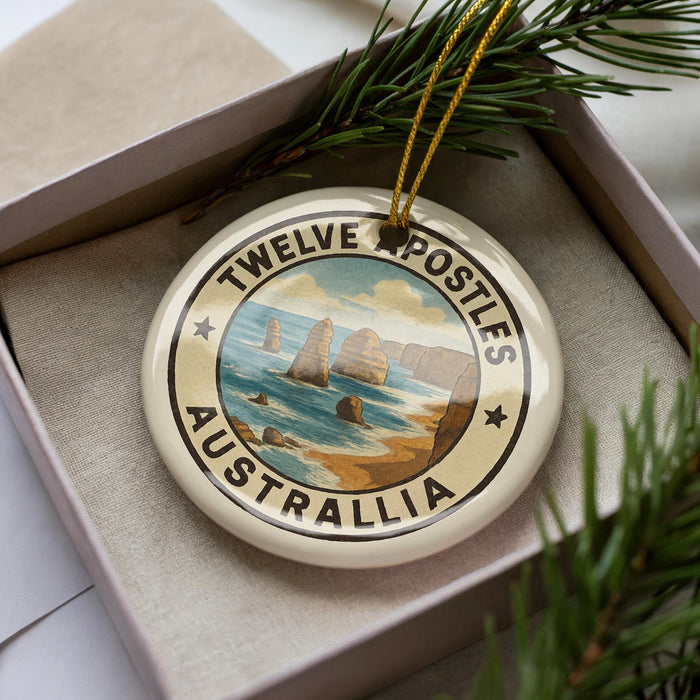 A decorative ornament in a box, featuring a circular design with a scenic image of the Twelve Apostles, a famous limestone stacks in Australia.