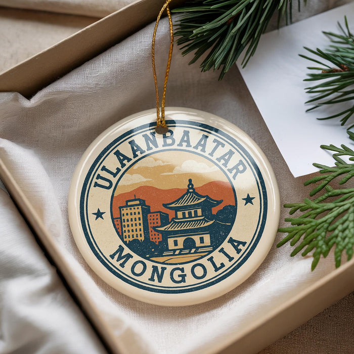 A decorative ornament with the text "ULAANBAATAR MONGOLIA" and an illustration of a building, placed on a surface with pine branches and a white paper.