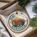 A decorative ornament with the text "ULAANBAATAR MONGOLIA" and an illustration of a building, placed on a surface with pine branches and a white paper.
