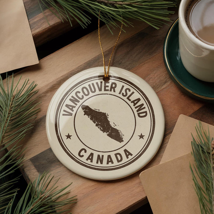 A circular ornament with the text "VANCOUVER ISLAND CANADA" printed on it, surrounded by pine branches and a cup of coffee on a wooden surface.