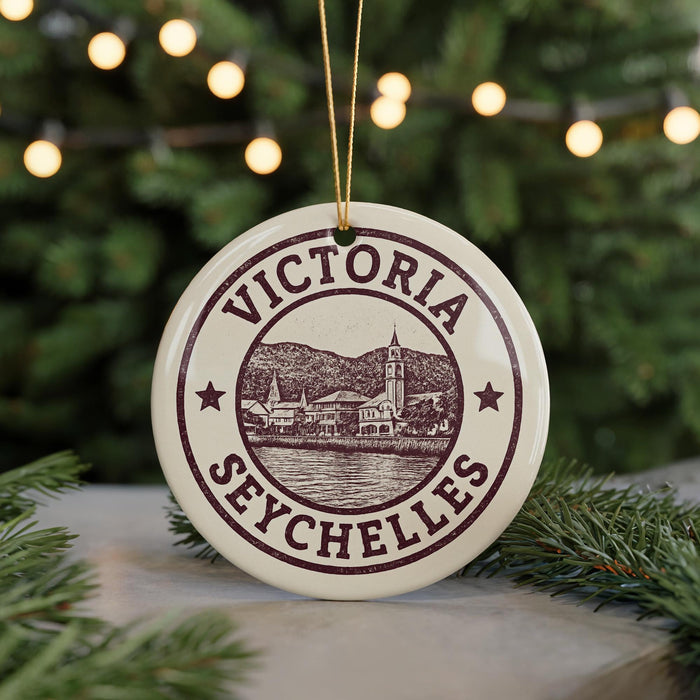 A round ornament with the text "VICTORIA SEYCHELLES" and an illustration of a town or village, hanging from a string.
