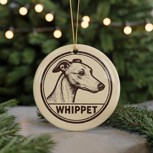 A round ornament featuring a drawing of a greyhound dog with the word "Whippet" written below it, hanging from a string.
