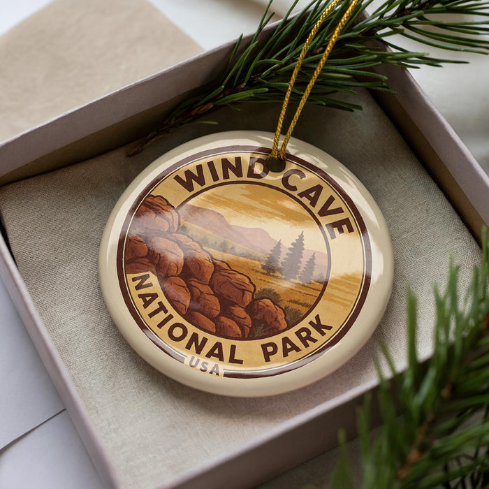 A decorative ornament featuring the text "WIND CAVE NATIONAL PARK USA" and an illustration of a scenic landscape with mountains and pine trees.