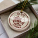 A decorative ornament in a box, featuring a circular design with a building and the text "XIAN CHINA" printed on it.